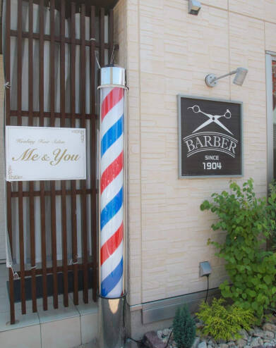 「BARBER SINCE 1904」と書かれた看板と理髪ポールが並ぶ美容室の外観。