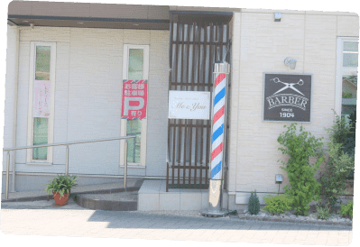 バーバーポールと「BARBER SINCE 1904」の看板が設置された理容院のエントランス