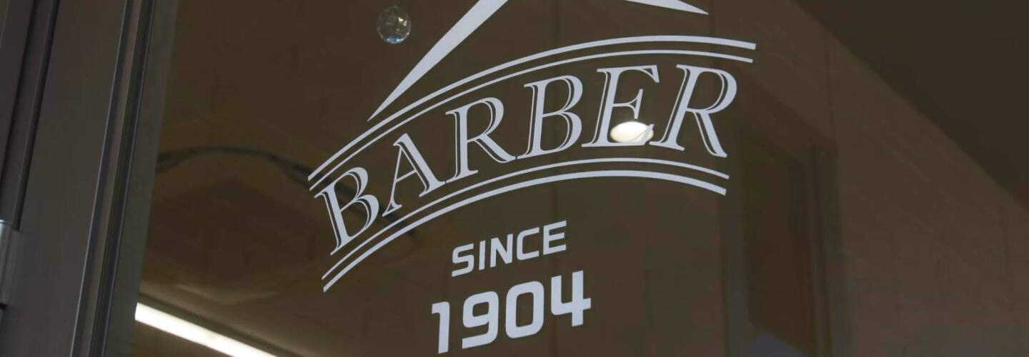 「BARBER SINCE 1904」と印字されたガラス扉、歴史を感じさせるバーバーショップのエントランス